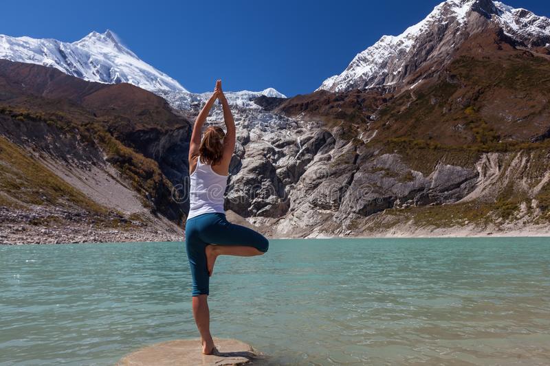 woman doing yoga excercises near big lake manaslu circuit trak nepal woman doing yoga excercises near big lake 99730305